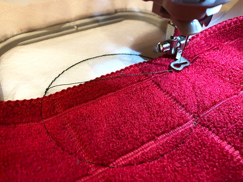 https://www.machineembroiderygeek.com/wp-content/uploads/2021/12/in-the-hoop-towel-topper-tack-down-stitching-on-towel.jpg