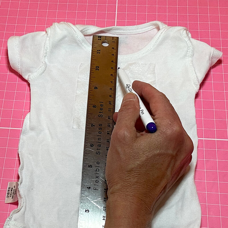 Turn shirt or onesie inside out
Turn onesie inside out. Fuse a piece of fusible poly mesh (larger than the size of the design you are stitching out) to inside of the onesie. Then locate the intended center of the design.